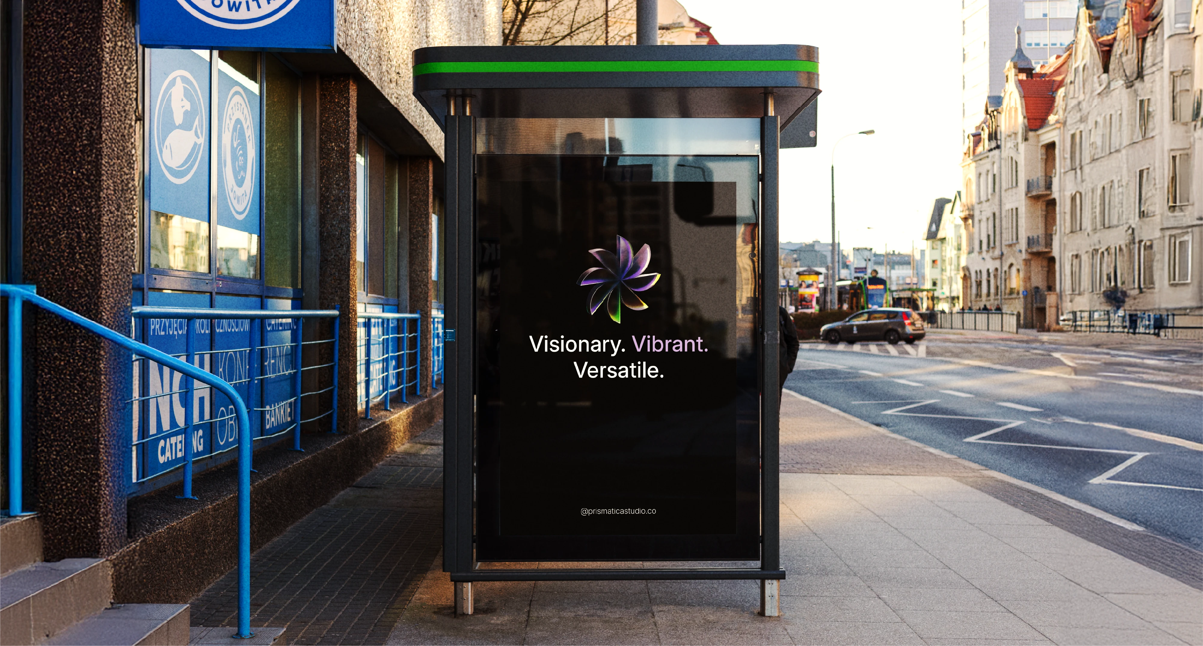 The Prismatica Studio branding on a bus stop advertisement, demonstrating its impactful presence in an urban environment, embodying the "Visionary. Vibrant. Versatile." tagline at scale.