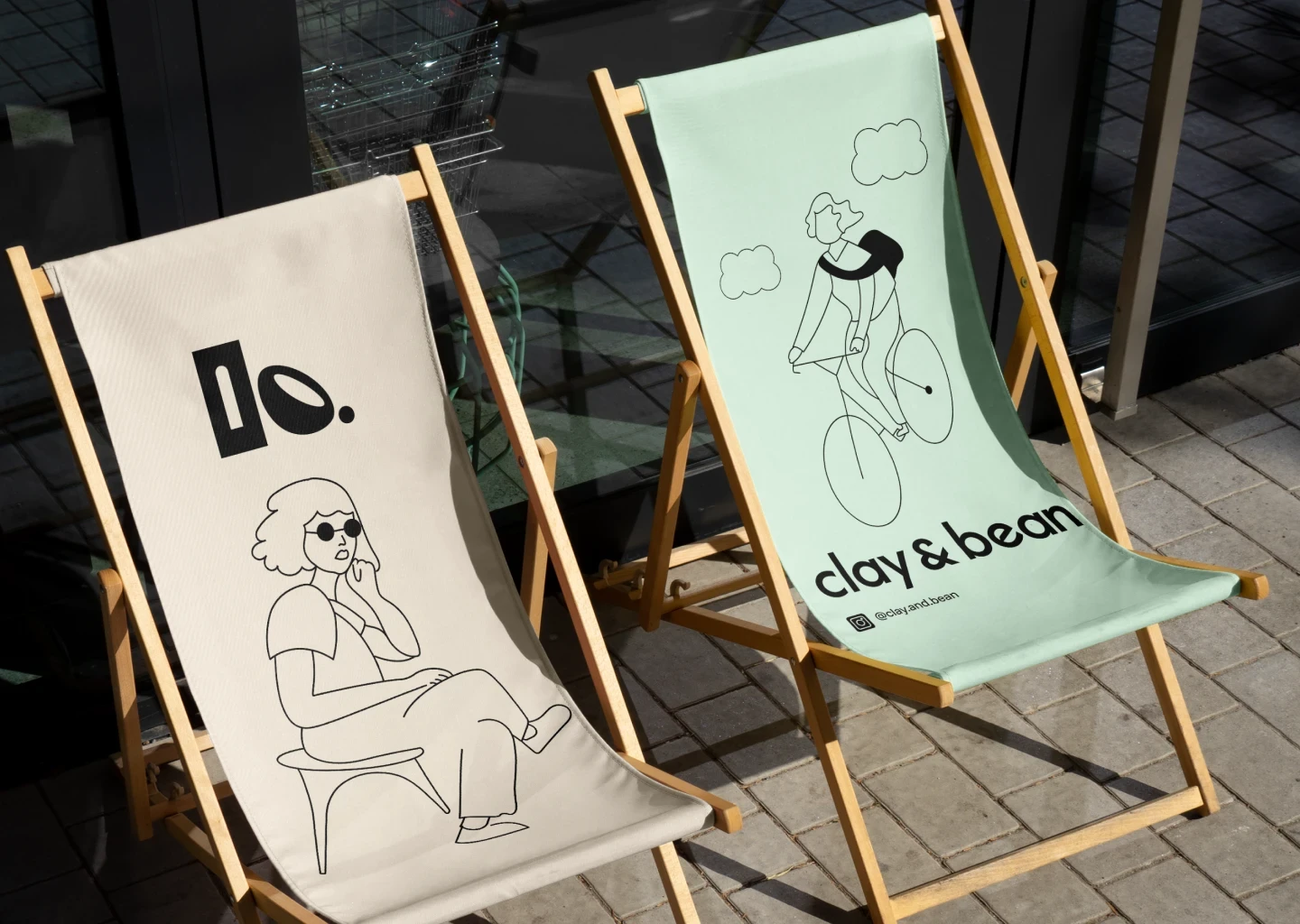 Clay & Bean branded sun chairs with line art illustrations, placed outside on a stone pavement.