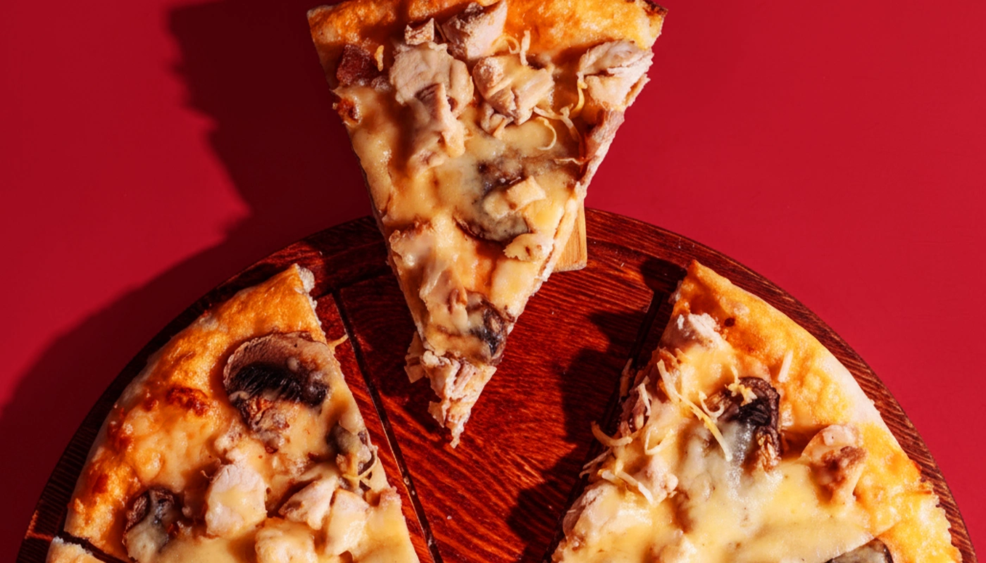 Close-up pizza slice on wooden board with red background for Pizzino branding.