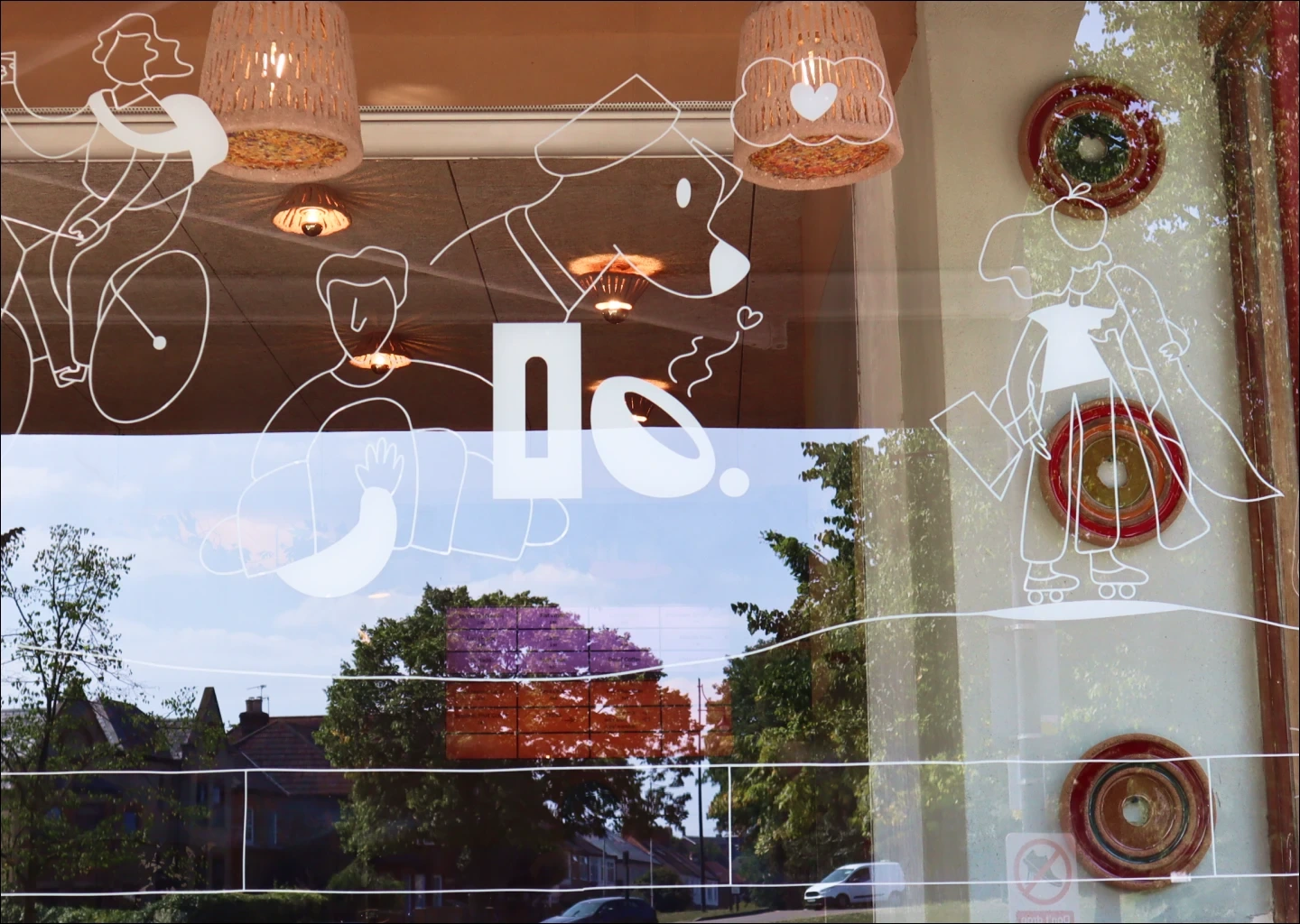 Clay & Bean window art with line illustrations of people, dog, and coffee, reflecting outdoors