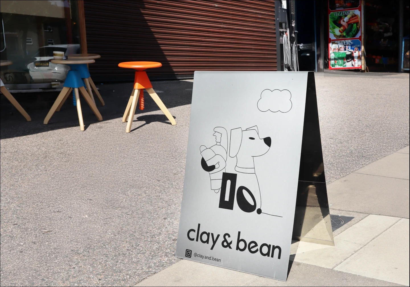 Clay & Bean A-frame sidewalk sign with dog line art logo and branding placed outside the café entrance.