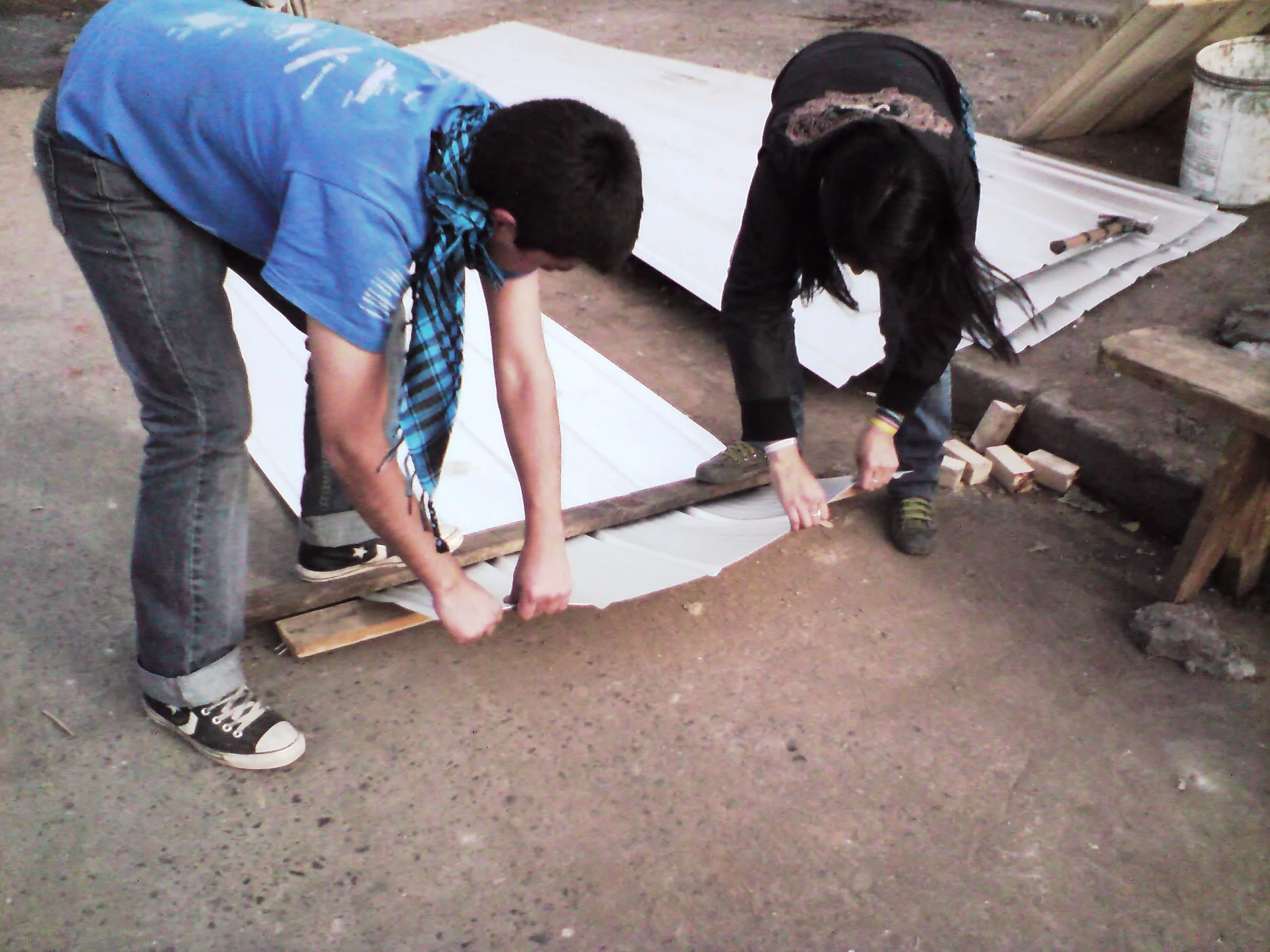 Bending the zinc roofing into a gable using a plank. Mediagua constructed near Estacion Central in Santiago, June 2010. Photo by Ben Angel.