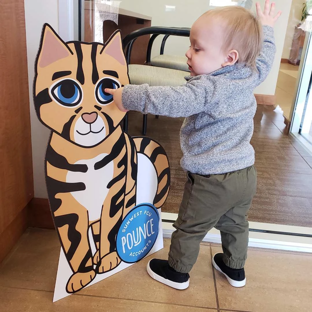 Child interacting with in-branch cardboard cutout of Pounce