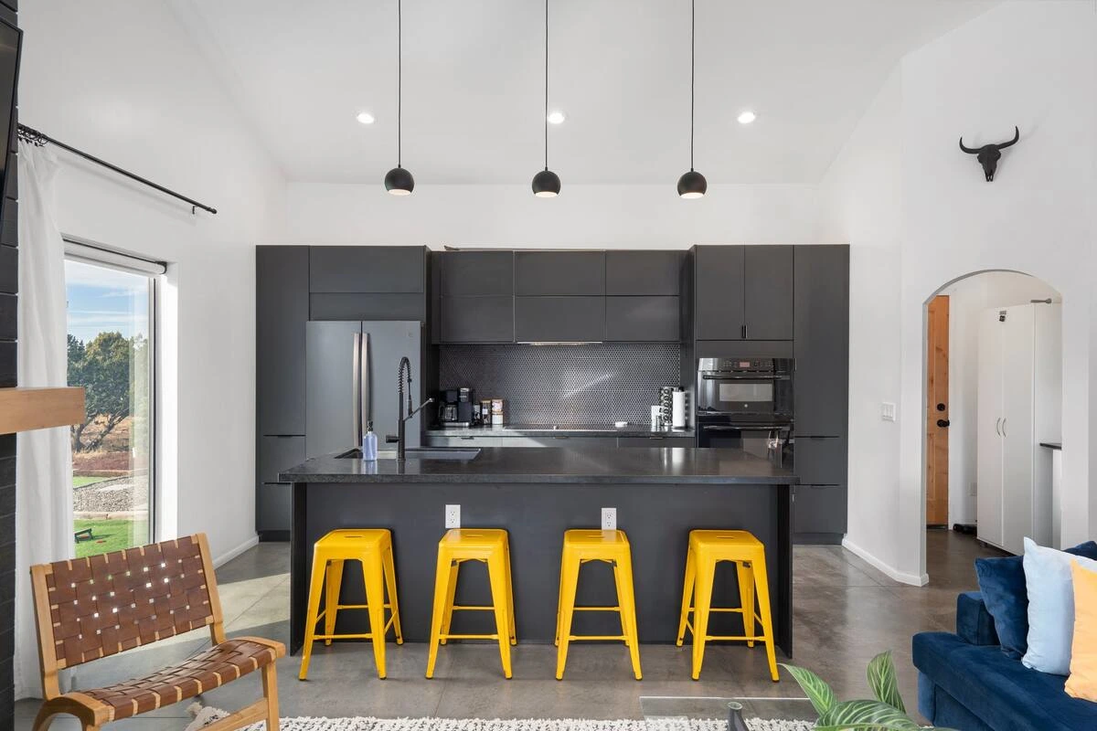 High contrast kitchen - with modern light fixtures and bold color stools. 