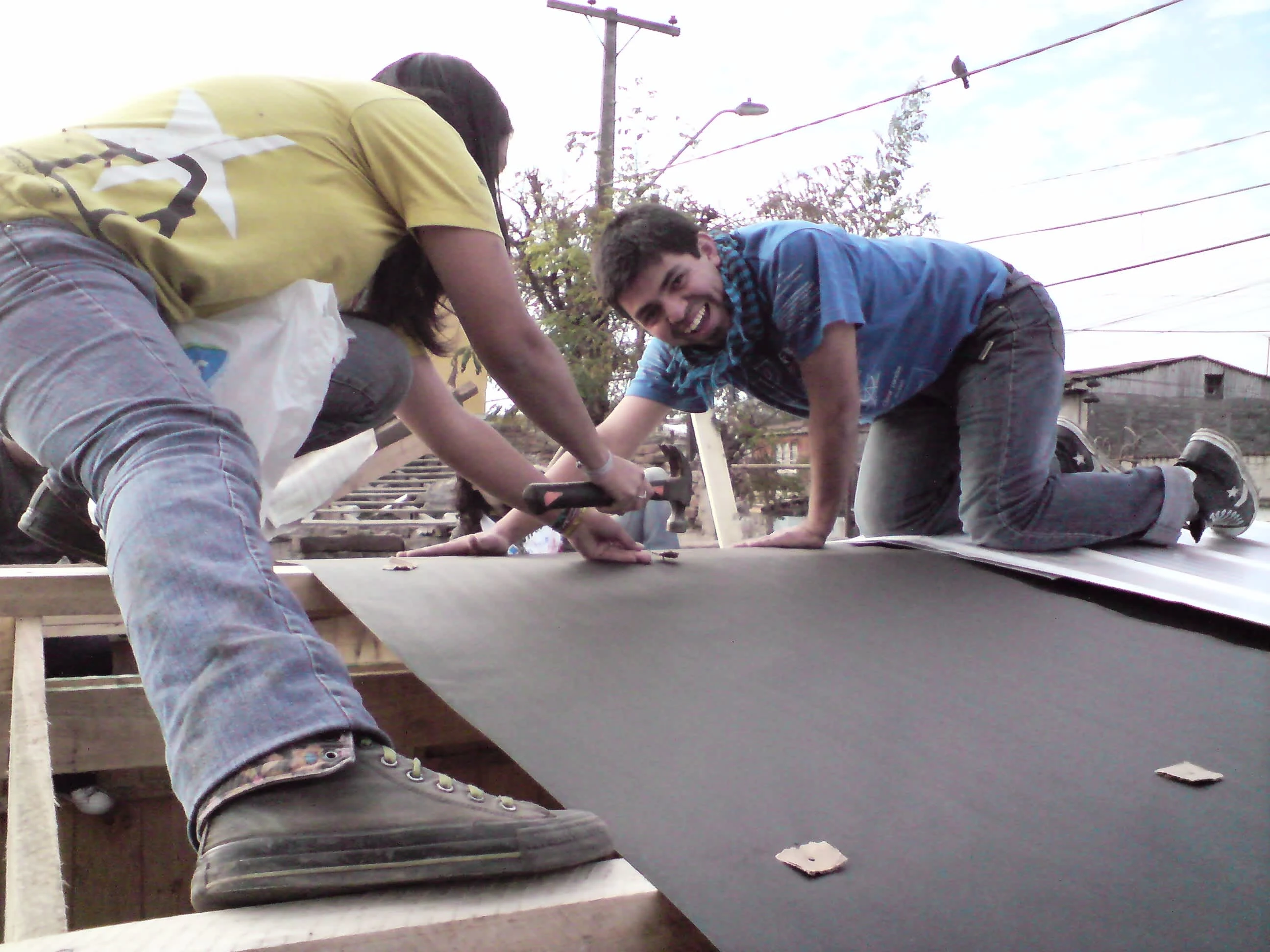 Tacking in tar paper onto the rafters at a mediagua near Estacioni Central in Santiago in June 2010. Photo by Ben Angel