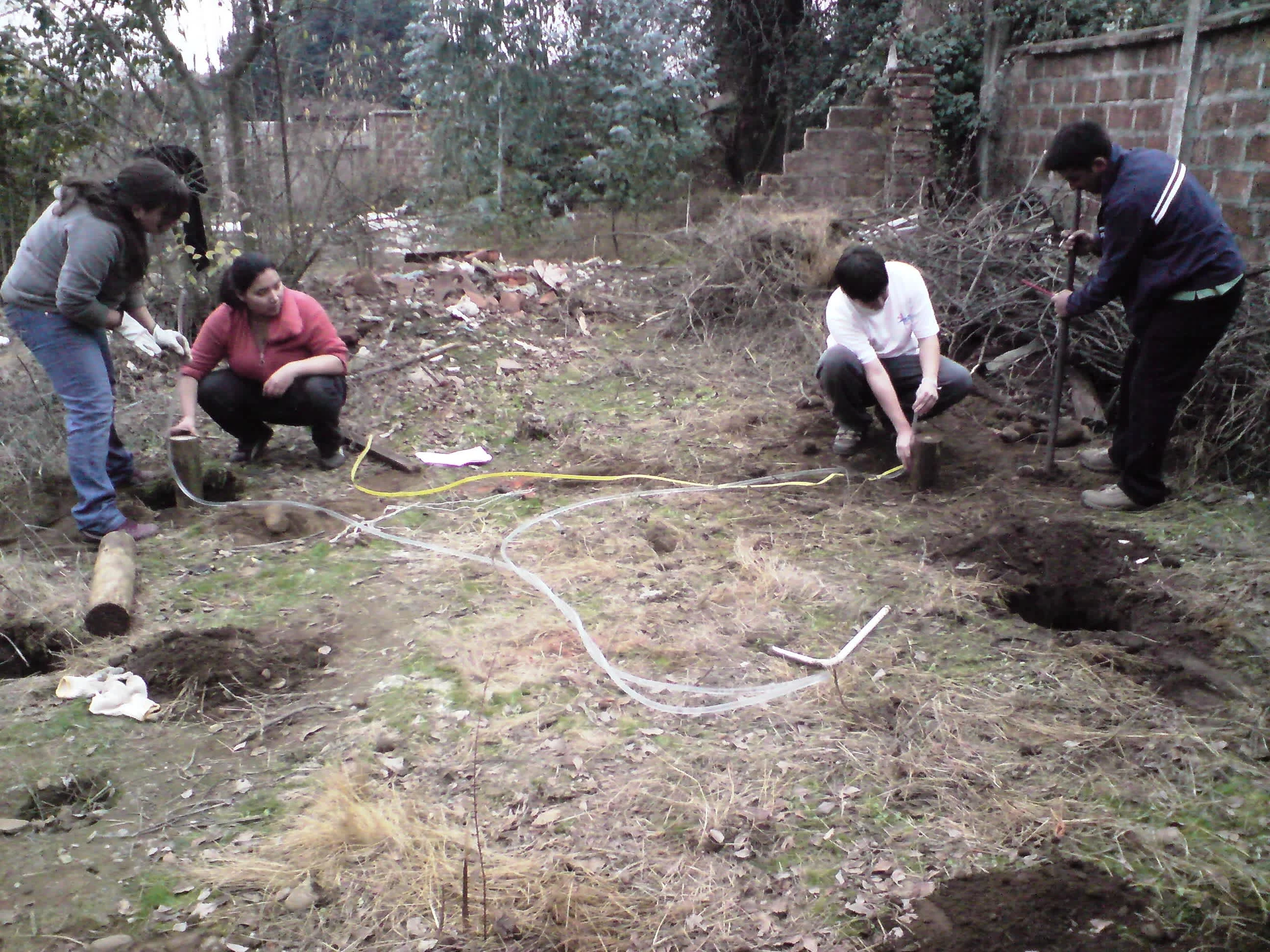 Volunteer team at Linares chicking pile levels using a plastic tube filled with water. If the levels are flush with the top of all piles on both sides, then the floor they support will be even. Photo by Ben Angel, May 2010.