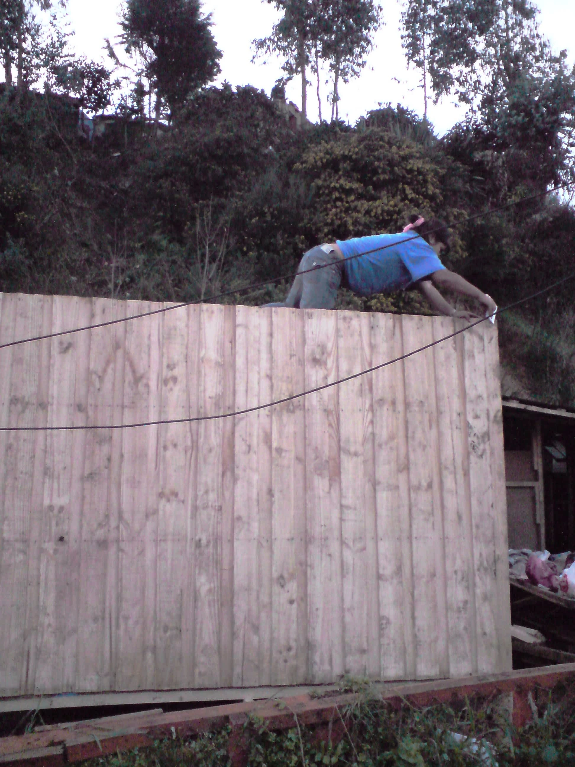 Stapling in tar paper onto the roof of a two-mediagua living place at Lota, June 2010. Photo by Ben Angel.