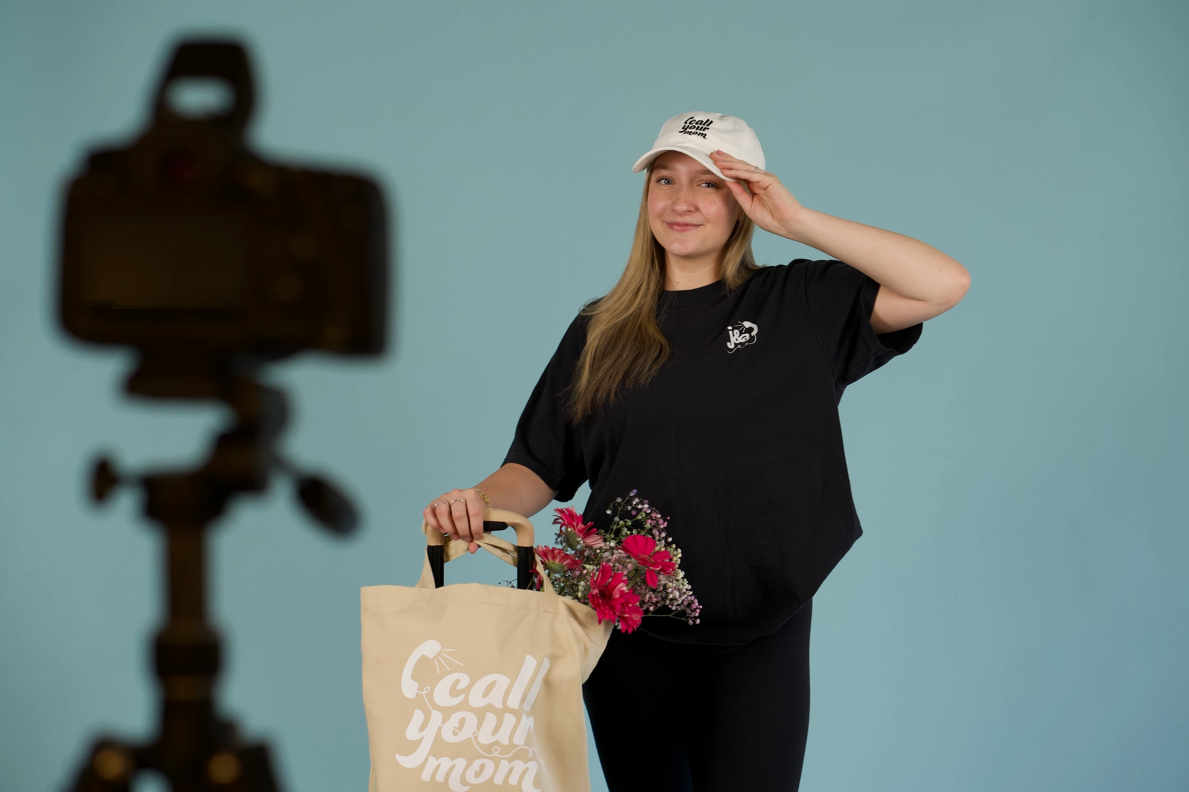 Annica wearing the 'Call Your Mom" T-shirt, Dad hat, and tote bag