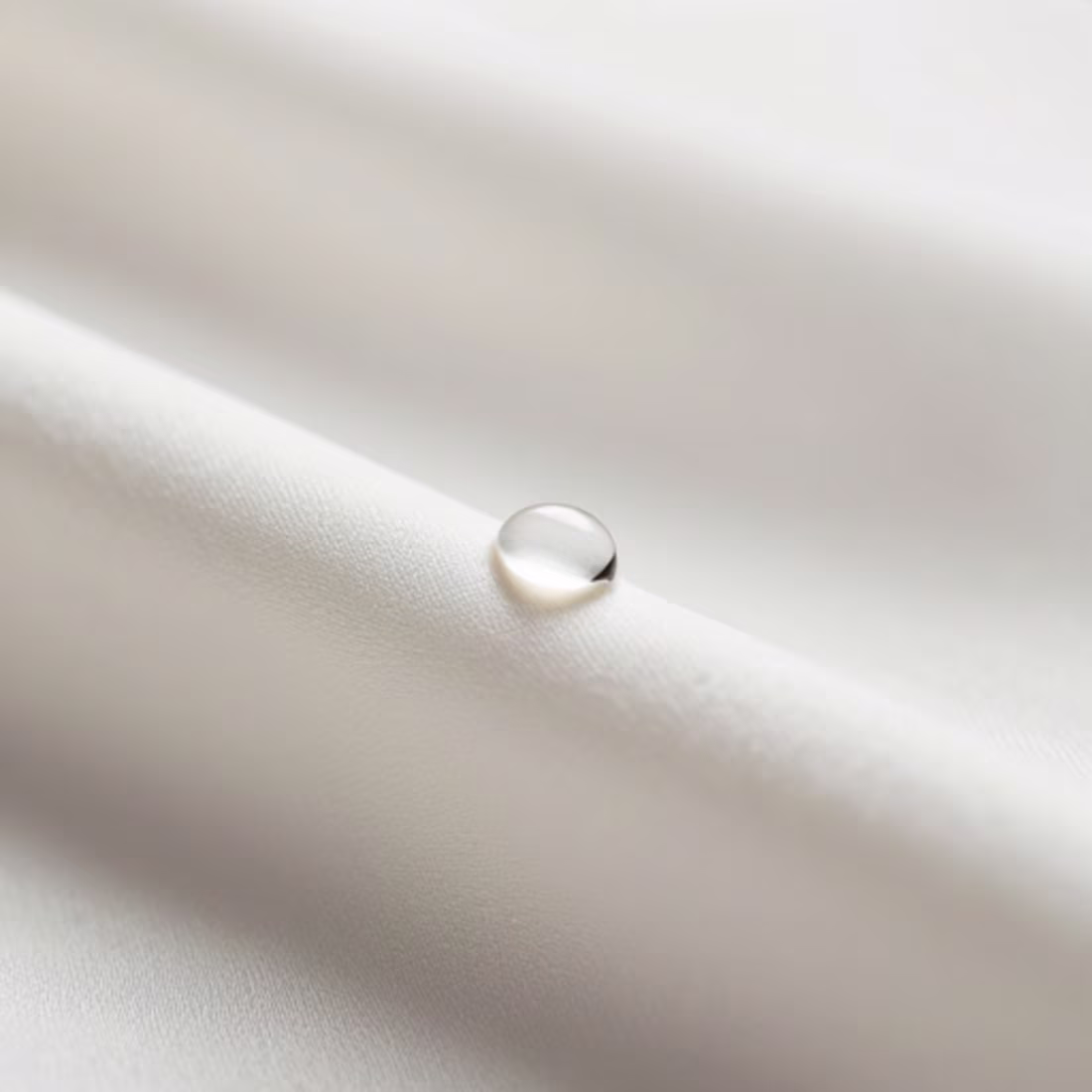 Cover image for A drop of water on the weave of a silk fabric.